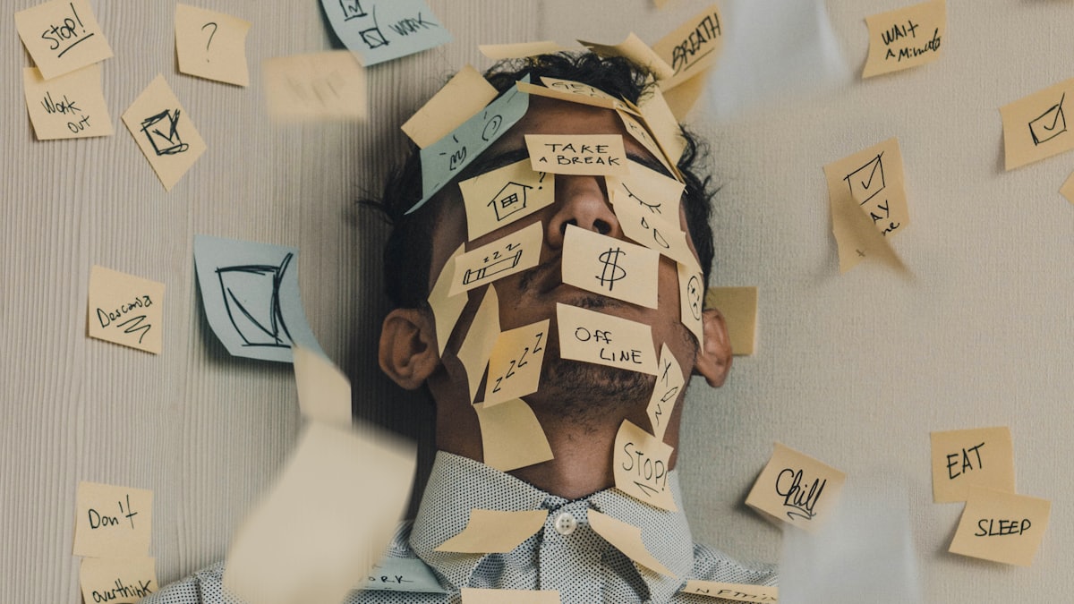 A person at a desk covered in sticky notes, showing a mind that feels overwhelmed